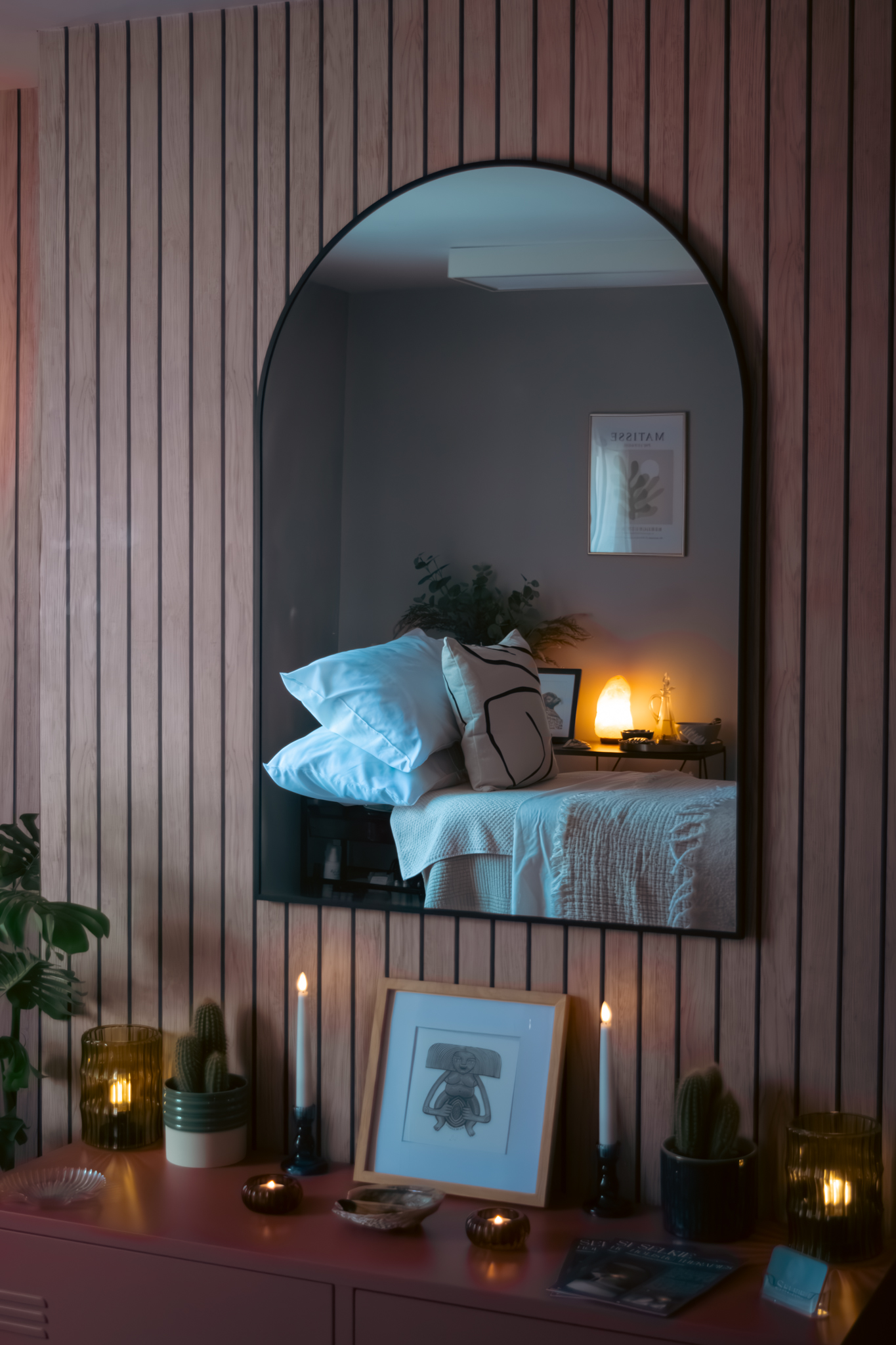 The arched mirror on the slatted wall, reflecting the made-up treatment bed
