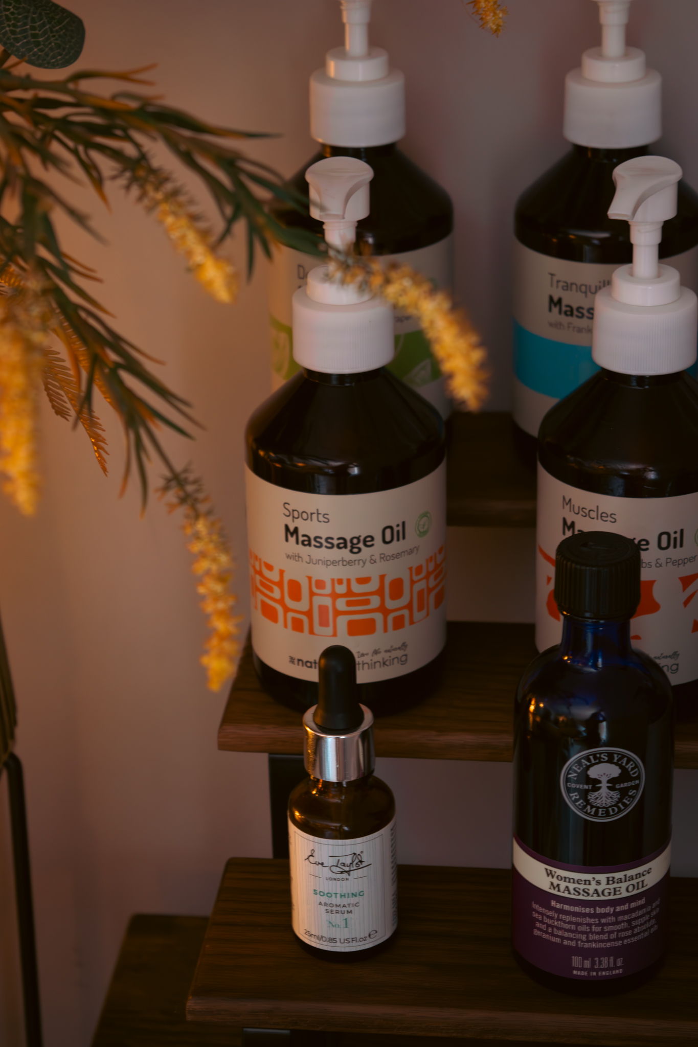 Massage oils on a shelf with dried flowers