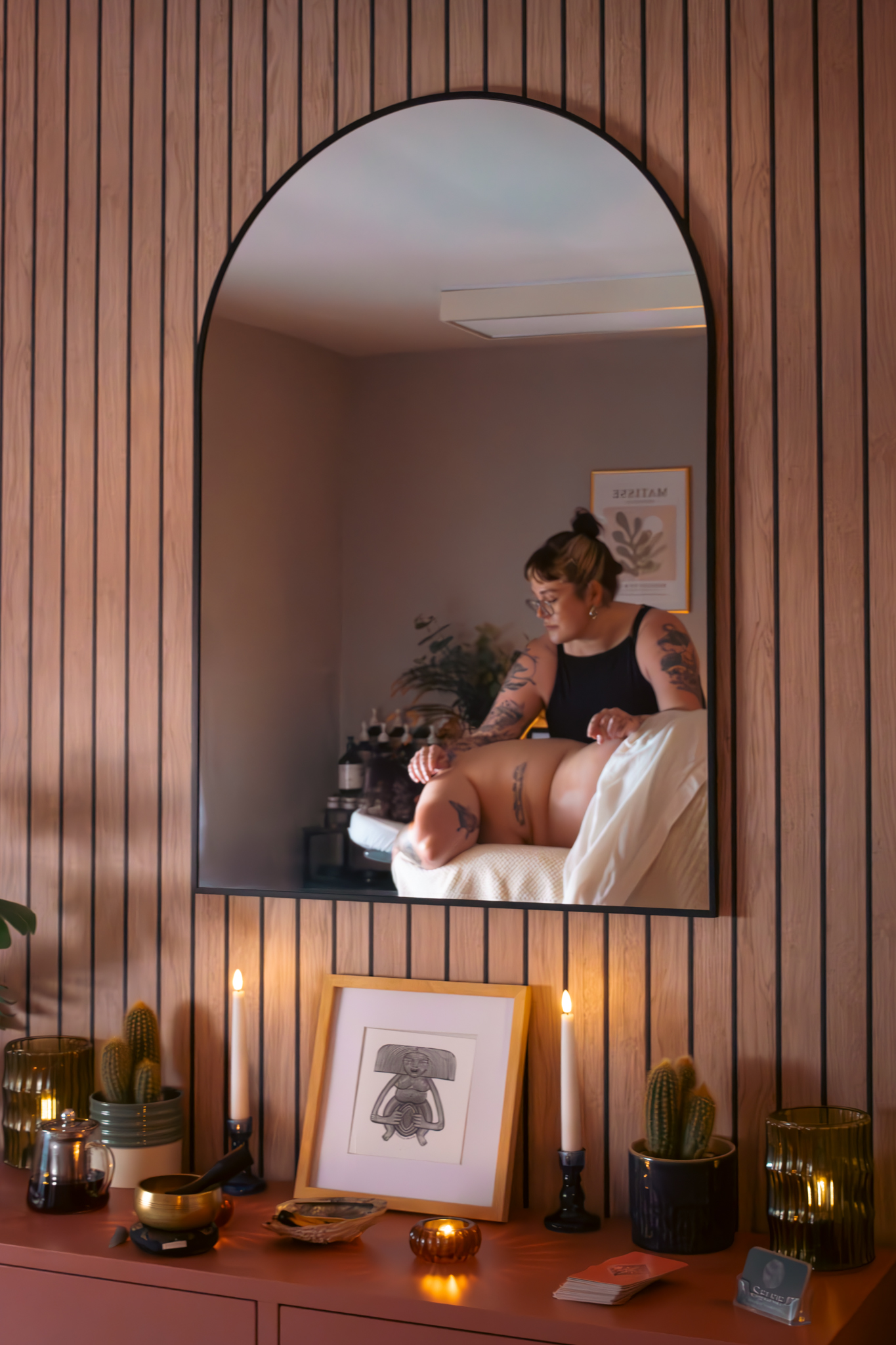 Abbi massaging a client, reflected in the arched mirror of the treatment room