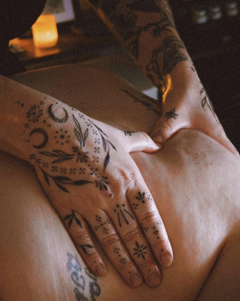 Abbi's tattooed hands mid-massage on a client's back