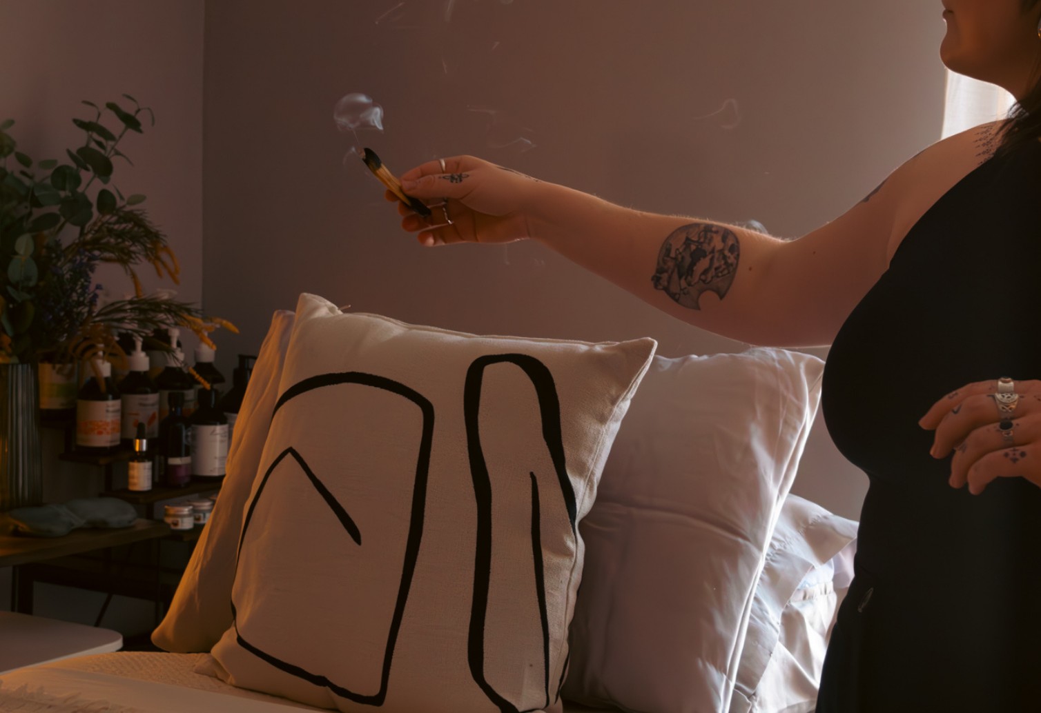 Abbi clearing the treatment room with incense beside the bed cushions